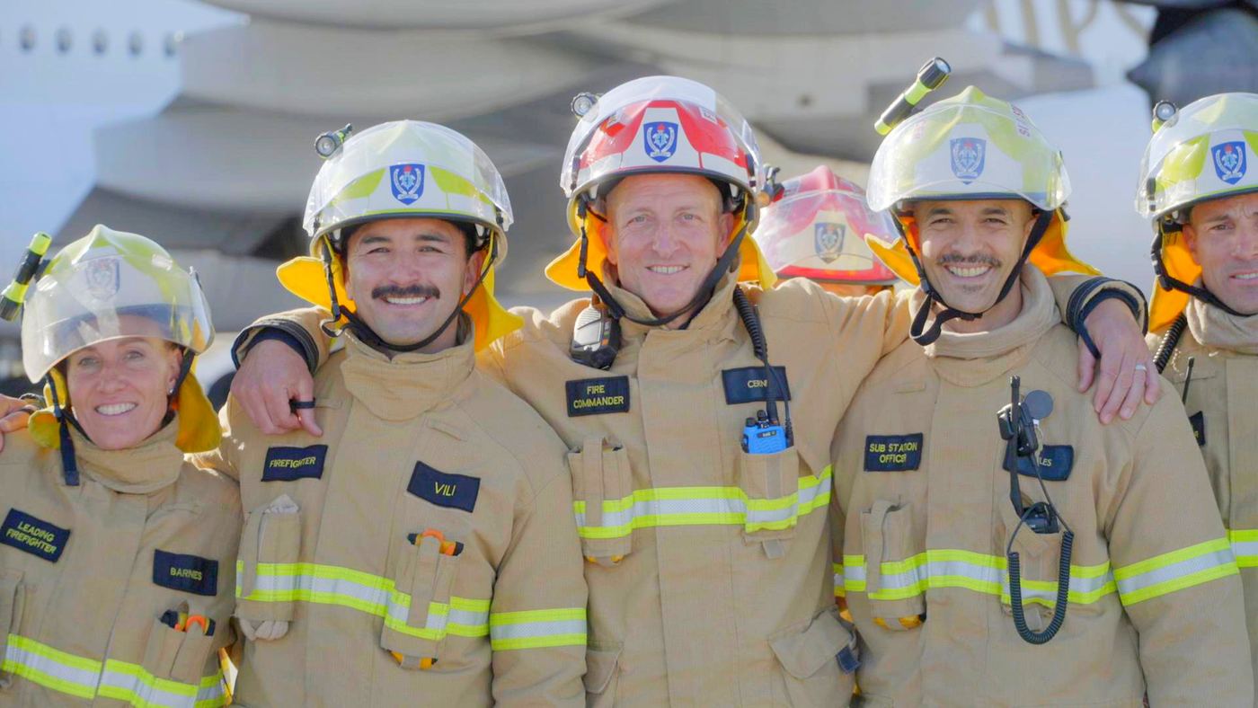 Firefighters in yellow gear, arms around each other