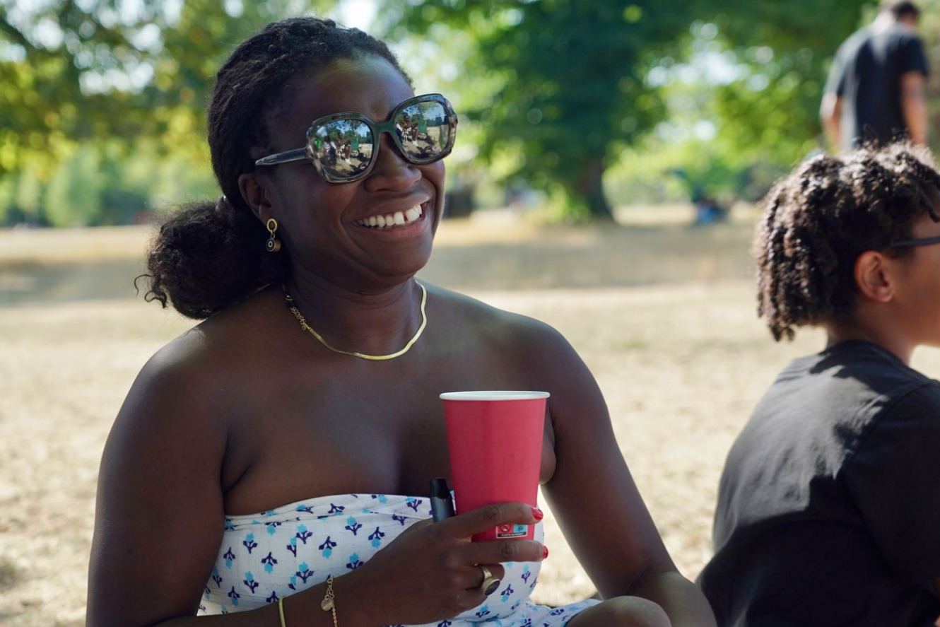 A woman in sunglasses smiling at a park party
