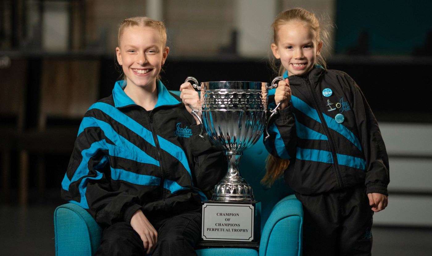 Two young calisthenics champions holding a trophy