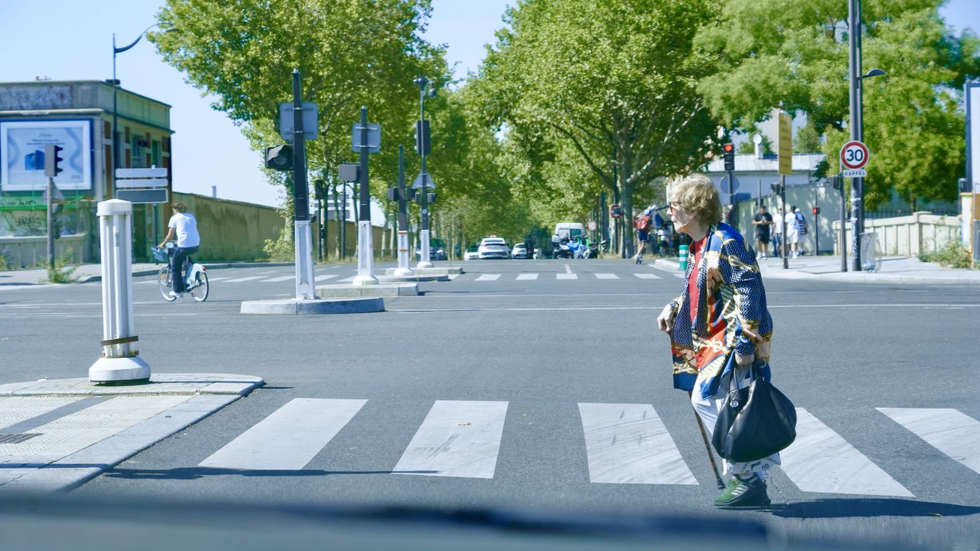 A woman crossing a leafy city street
