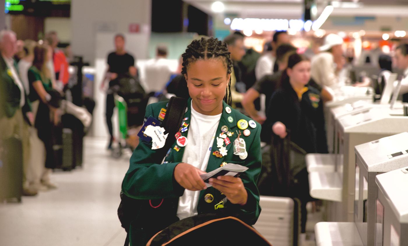 A young traveller with badges on her jacket at an airport