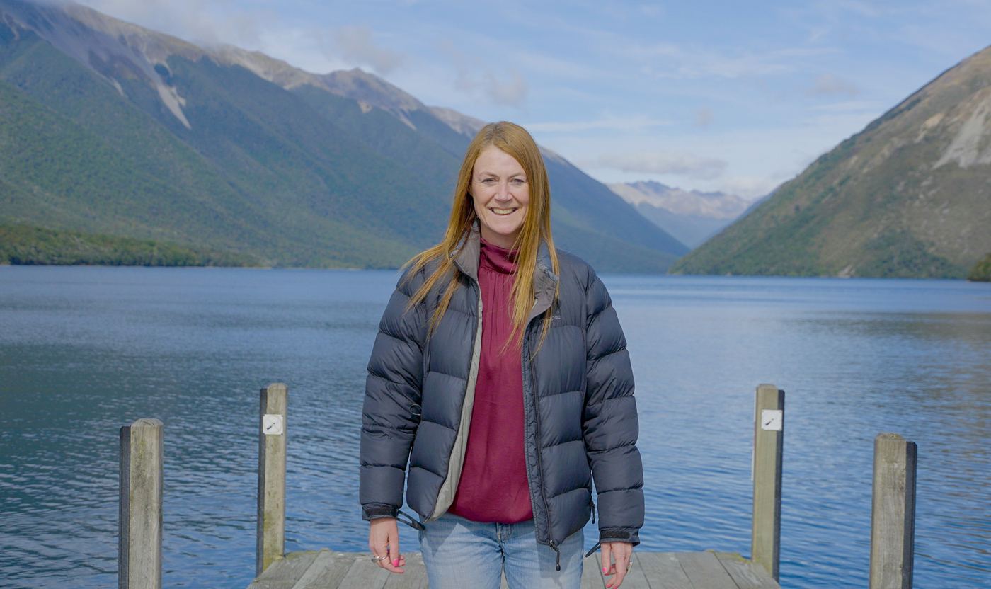 A woman on a jetty in front of a mountain lake
